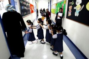 Teacher with pupils in a classroom, heading an article on the GCC teacher shortage