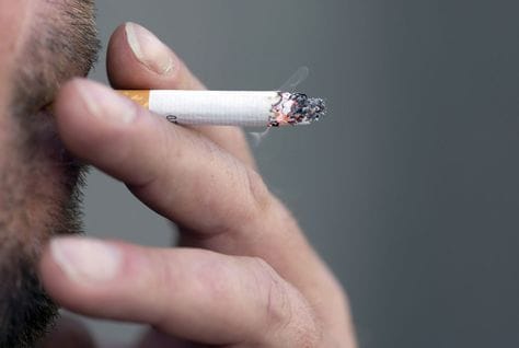 Cigarette in an ashtray, heading an article on a possible UAE public smoking ban